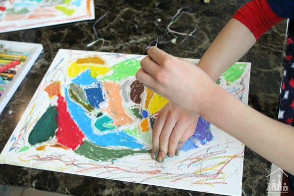 Child peeling glue off a glue resist art project