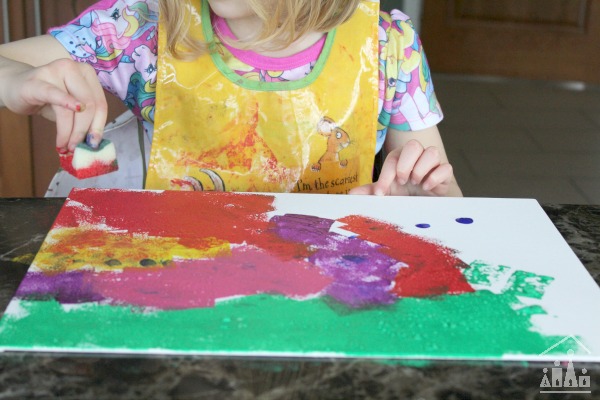 Child sponge painting on a piece of canvas
